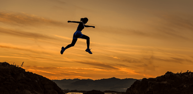 Person jumping over a cliff to illustrate making a change