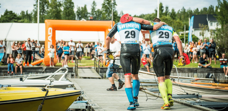 Simlöpare som stöttar varandra vid mållinjen